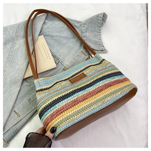 Close-up of colorful woven straw tote bag with brown faux leather trim and fashion label