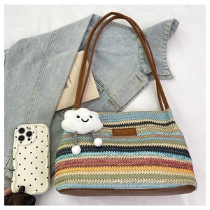 Detail of colorful striped woven tote bag featuring a leather tag and cloud smiley charm