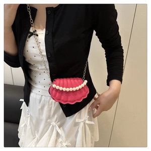 Detail of shell-shaped crossbody bag in hot pink with pearl trim and gold chain