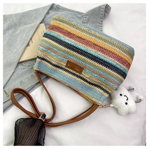 Close-up of rainbow striped woven crossbody bag with brown leather strap and cloud charm