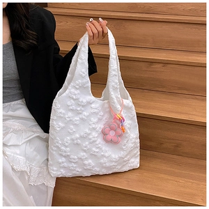 Detail of white tote bag featuring 3D floral embroidery and a pink flower pendant