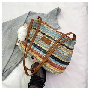 Close-up of multicolored woven tote bag with brown leather straps and plush bunny charm