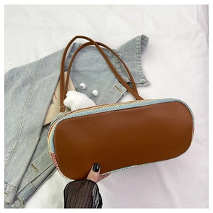Close-up of woven tote bag featuring colorful textures, brown leather base, and cloud charm