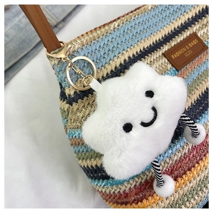 Close-up of a white plush cloud charm with smiling face on a woven tote bag