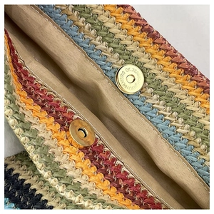 Detail of multi-color woven tote bag featuring golden magnetic snap closure and fabric lining