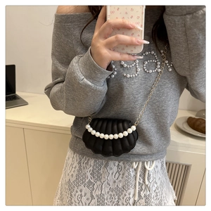 Detail of shell-shaped mini crossbody bag with pearl handle and golden chain strap