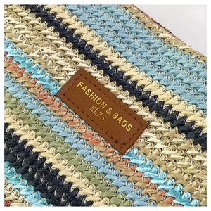 Close-up of woven tote texture with blue, beige fibers and brown leather logo patch