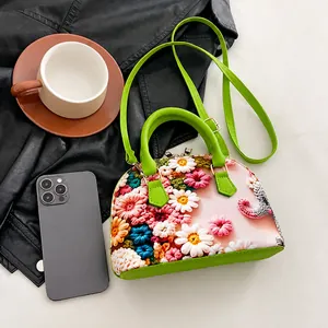 Detail der Blumenstickerei auf shellförmiger Handtasche mit neongrünen Griffen