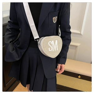 Détail du sac bandoulière tissé en forme de cœur avec broderie SM blanche et sangle