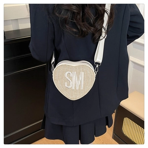 Détail d'un sac bandoulière tissé en forme de cœur avec broderie SM sur sangle