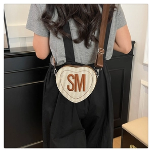 Détail du sac bandoulière en cœur tissé avec initiales SM et bandoulière ajustable