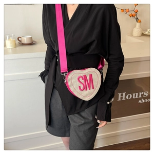 Détail d'un sac bandoulière en forme de cœur avec texture tissée et broderie SM