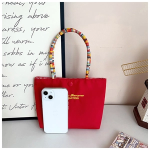 Detail of red nylon mini tote bag featuring colorful beaded handles and snap button closure
