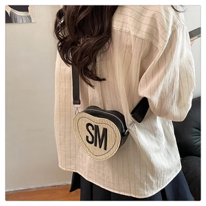 Détail d'un sac bandoulière tressé en forme de cœur avec broderie SM et large sangle