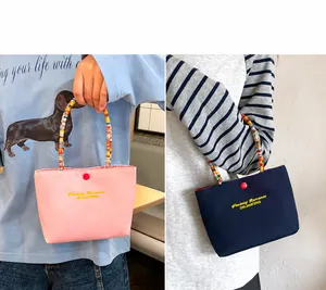 Detalle de mini bolsos de nailon con asas de cuentas arcoíris y bordado frontal