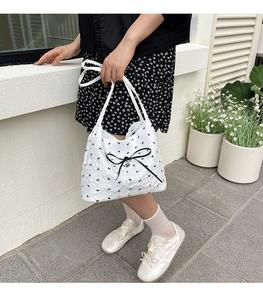 Detail einer weißen gesteppten Shopper-Tasche mit schwarzen Schleifen und elegantem Band