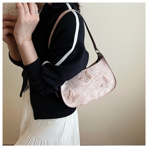 Détails de papillons 3D et motifs floraux en relief sur un sac hobo rose porté par le mannequin