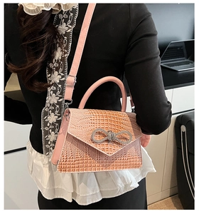 Detailed close-up of pink croc-embossed handbag with a sparkling rhinestone bow buckle