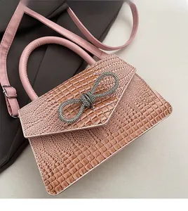 Detail of pink faux crocodile leather handbag with a sparkling rhinestone bow buckle
