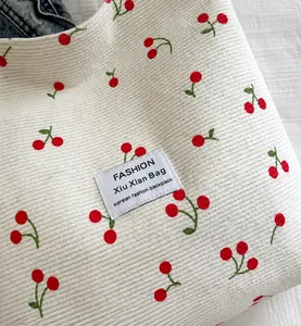 Dettaglio della borsa tote in velluto a coste bianco con motivi di ciliegie e logo