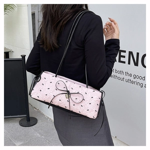 Détail du sac sous l'aisselle plissé rose avec nœuds noirs et breloque en cœur