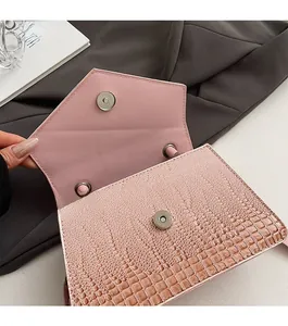 Detail of pink croc-embossed small crossbody bag showing dual magnetic snap closure