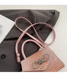 Detail of pink croc-embossed handbag featuring a silver sparkling rhinestone bow clasp