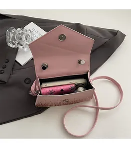 Pink crocodile-embossed handbag showing interior space for phone and wallet items