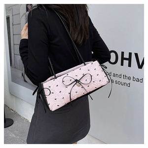 Détail du sac à main plissé rose avec imprimés de nœuds noirs et grand nœud en soie