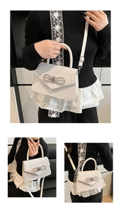 Close-up of white croc-embossed handbag featuring a sparkling rhinestone bow detail