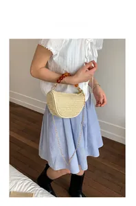 Detail of beige woven straw handbag with amber bead handle and gold chain strap