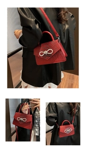 Detail of red crocodile texture bag with silver rhinestone bow and adjustable strap