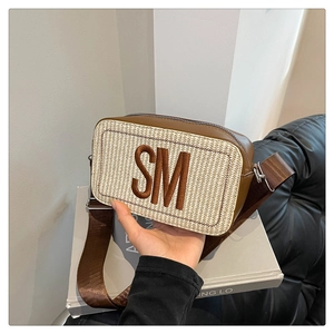 Detail der gewebten Stroh-Umhängetasche mit Logo-Stickerei und breitem Nylon-Schultergurt