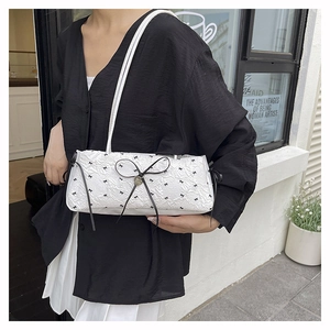 Détail d'un sac à bandoulière blanc avec imprimé nœud noir et texture plissée