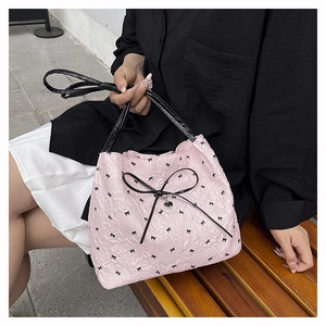 Detailaufnahme der rosa gesteppten Tasche mit schwarzen Schleifen und Textur