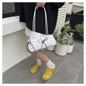 Détail du sac baguette blanc de style français avec imprimés nœuds et rubans noirs