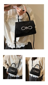 Detail of crocodile pattern faux leather handbag with sparkling rhinestone bow accent