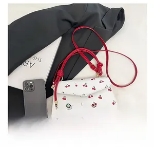 Detail showing white PU leather crossbody bag with cherry print and red glossy edges