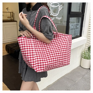 Model wearing a large red and white gingham canvas tote bag in a casual street setting