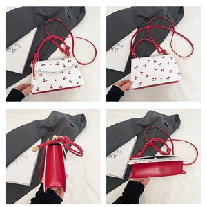 Detailed views of white cherry print handbag featuring red leather trim and gold hardware