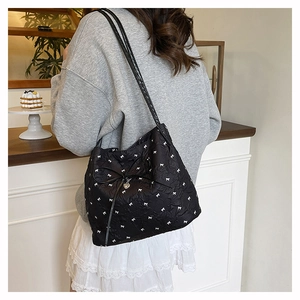 Details der schwarzen Stepptasche mit weißem Schleifenmuster und Herzanhänger