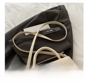 Close-up of beige shoulder bag featuring woven straw lid and smooth leather texture