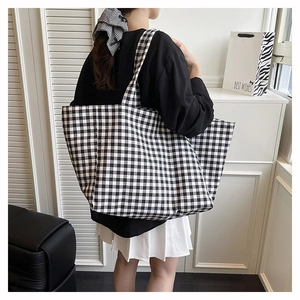 Vue détaillée du grand sac cabas en toile à carreaux noir et blanc porté par un mannequin