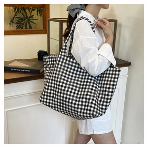 Classic black and white gingham canvas tote bag shown worn over the shoulder by a model