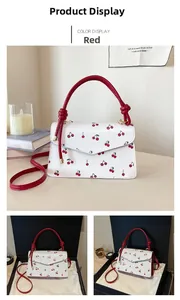 Detail of red cherry print handbag with elegant knot handle and matching shoulder strap