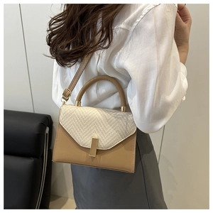 Detail of a khaki leather and straw woven crossbody bag with gold buckle on a model