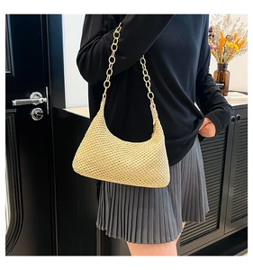 Detail van de handgeweven strooien hobo tas met een decoratieve gouden kettingband