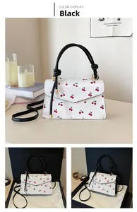 Macro detail of white leather crossbody bag with cherry print and gift packaging boxes