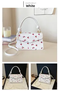 Detail of white leather handbag with cherry print and cylindrical knotted handle