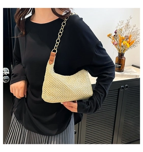 Detail van de handgeweven strooien tas met gouden ketting en bruine leren details